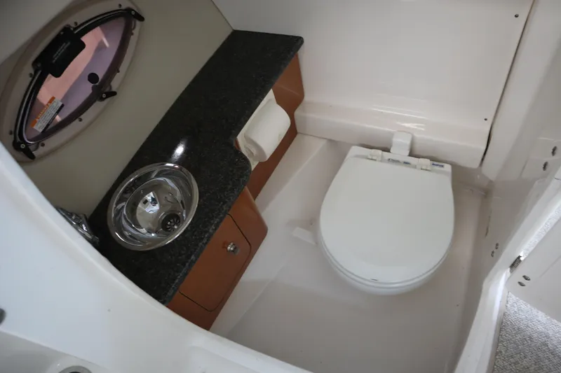 Slide: The Image of 2009 Chaparral Sunesta 244 boat bathroom with sink, toilet, and porthole window. - 21