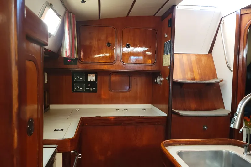 Slide: The Image of Interior of 1986 Beneteau Idylle 15.50 sailboat with wooden cabinetry and compact kitchen area. - 10