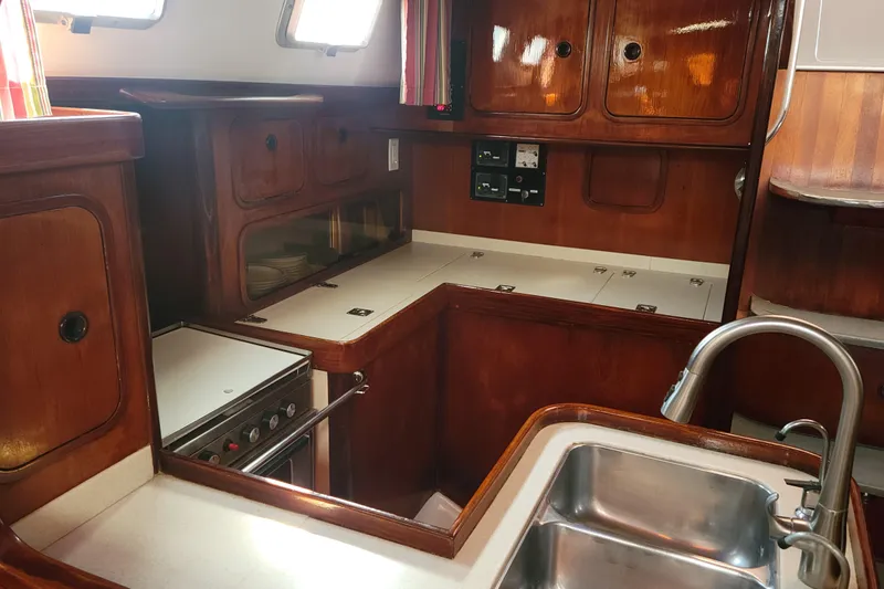 Slide: The Image of Interior of 1986 Beneteau Idylle 15.50 yacht kitchen with wooden cabinetry and stainless steel sink. - 11
