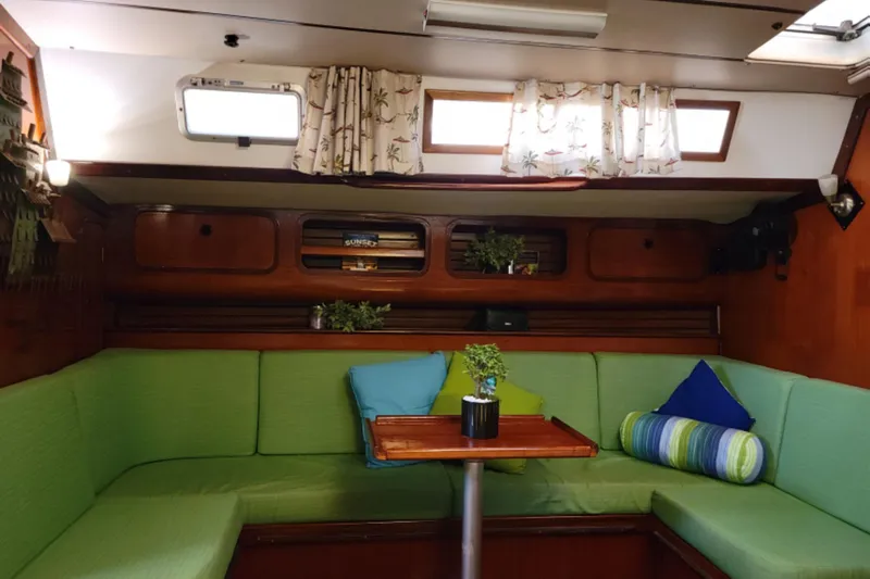 Slide: The Image of Cozy interior of 1986 Beneteau Idylle 15.50 sailboat with green seating and decorative pillows. - 13