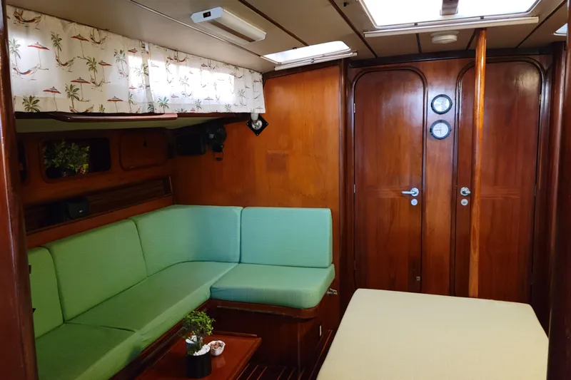 Slide: The Image of Interior of 1986 Beneteau Idylle 15.50 yacht with green seating and wooden paneling. - 14