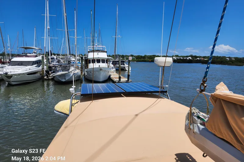 Slide: The Image of Beneteau Idylle 15.50 sailboat docked at marina with solar panels, clear sky, and calm waters. - 28
