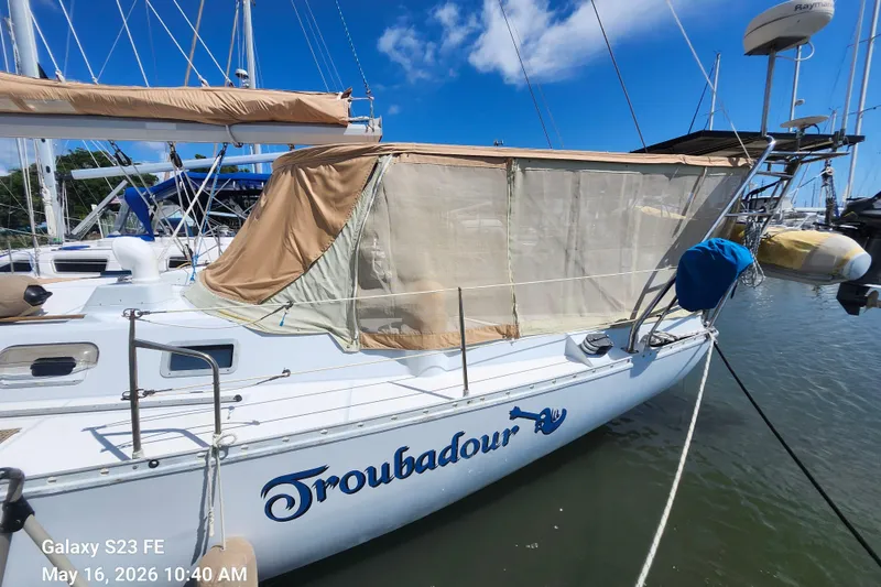 Slide: The Image of 1986 Beneteau Idylle 15.50 sailboat named "Troubadour" docked in a marina under clear skies. - 3