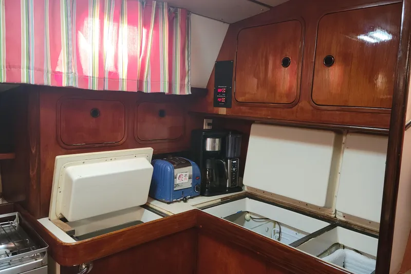 Slide: The Image of Galley of 1986 Beneteau Idylle 15.50 sailboat with wooden cabinets and appliances. - 51
