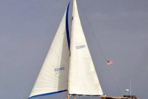Slide: The Image of 1986 Beneteau Idylle 15.50 sailboat with white sails and American flag. - 54