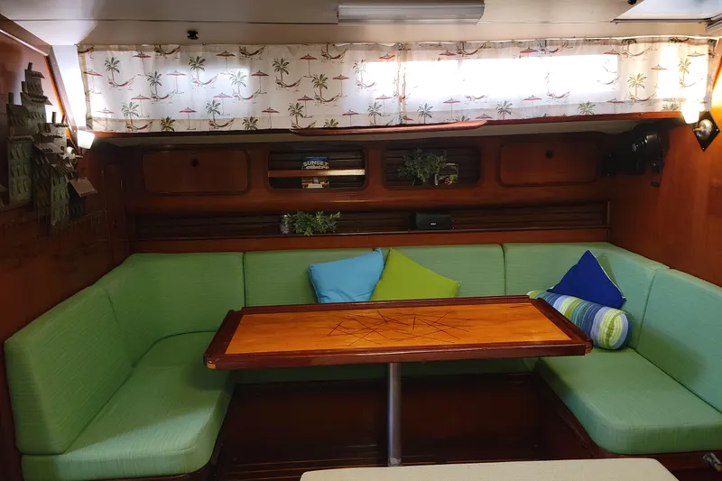 Slide: The Image of Interior of 1986 Beneteau Idylle 15.50 yacht with green seating and wooden table. - 8