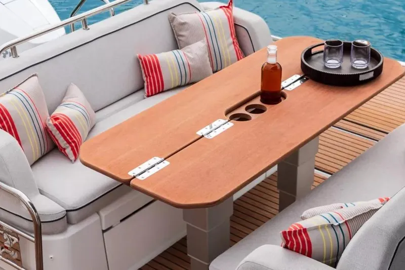 Slide: The Image of Luxury seating area on 2026 Beneteau Gran Turismo 35 yacht with wooden table and cushions. - 12