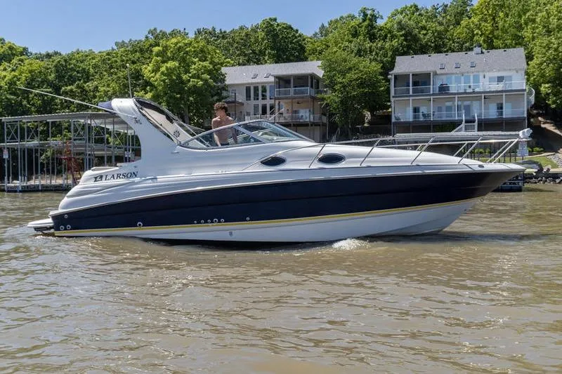 The Image of 2005 Larson Cabrio 290 boat cruising on a lake near waterfront homes. - 1