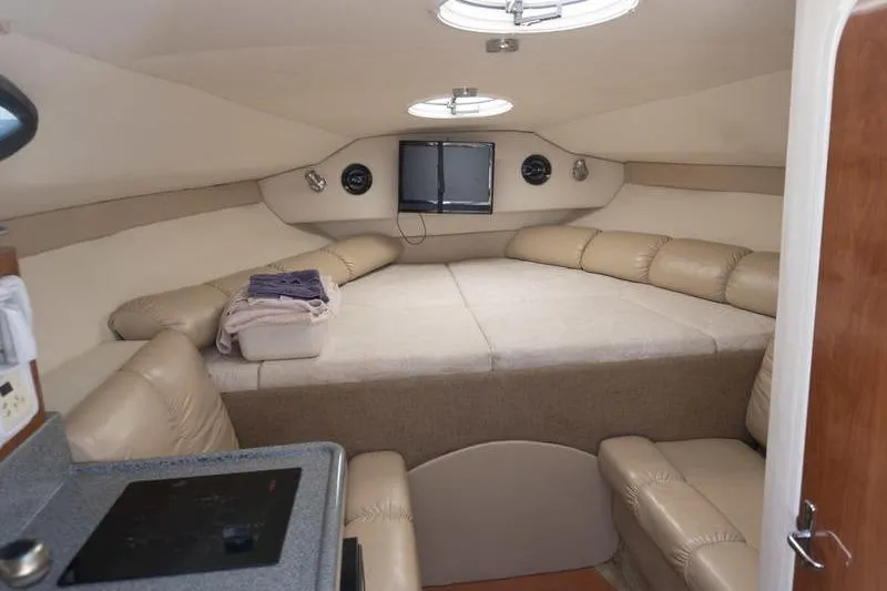 Slide: The Image of 2005 Larson Cabrio 290 cabin interior with beige seating and compact kitchenette. - 14