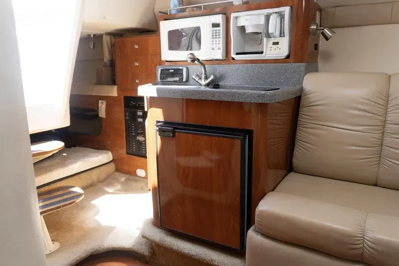Slide: The Image of 2005 Larson Cabrio 290 interior with kitchenette, featuring microwave, coffee maker, and compact fridge. - 16