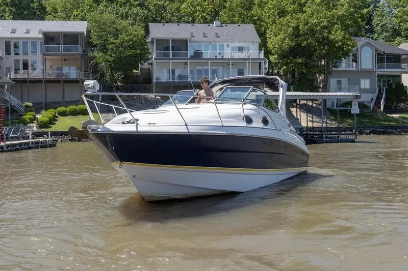 Slide: The Image of 2005 Larson Cabrio 290 boat cruising near waterfront homes on a sunny day. - 2
