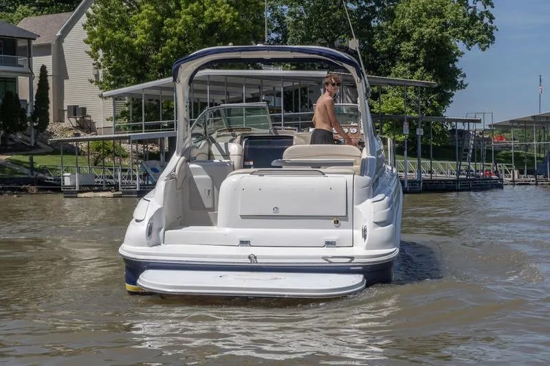 Slide: The Image of 2005 Larson Cabrio 290 boat on water near dock, person standing at helm. - 4
