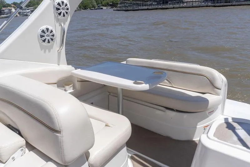 Slide: The Image of 2005 Larson Cabrio 290 boat interior with seating and table on a sunny day. - 7