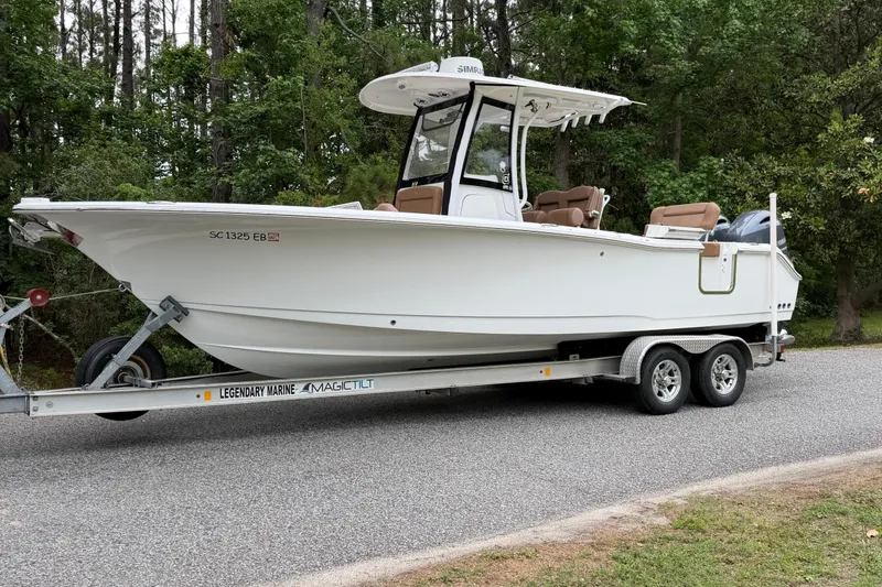 The Image of 2019 Sea Hunt Gamefish 25 boat on trailer, parked on roadside with forest background. - 0