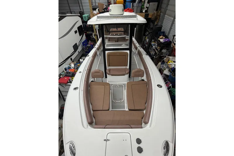 Slide: The Image of 2019 Sea Hunt Gamefish 25 boat interior with brown seating, stored in a garage. - 20