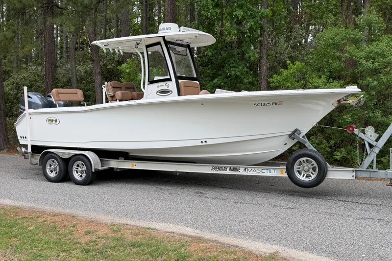 Slide: The Image of 2019 Sea Hunt Gamefish 25 boat on trailer, parked on a forested road. - 3