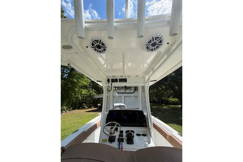 Slide: The Image of 2019 Sea Hunt Gamefish 25 boat console with steering wheel and electronics under a sunny sky. - 31