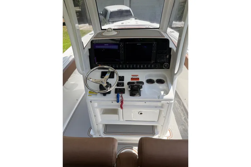 Slide: The Image of 2019 Sea Hunt Gamefish 25 helm with steering wheel, controls, and navigation screens. - 4