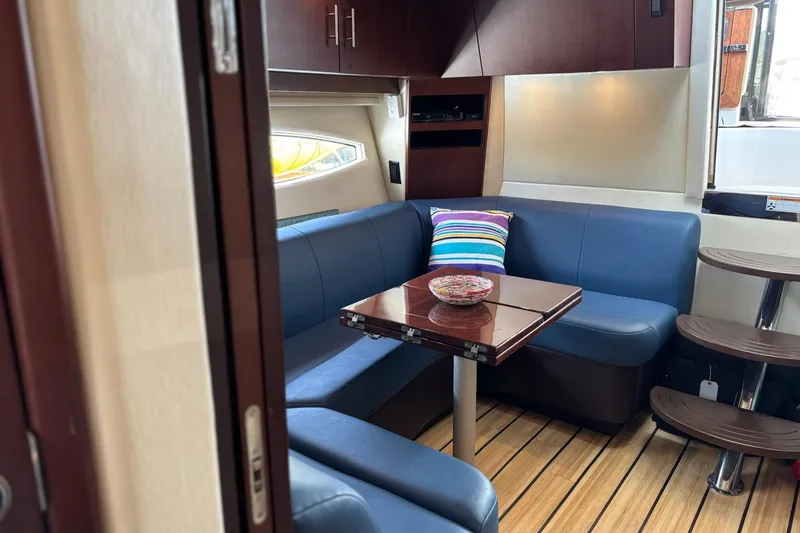 Slide: The Image of Interior of 2015 Regal 42 Sport Coupe with blue seating, wooden table, and striped pillow. - 19