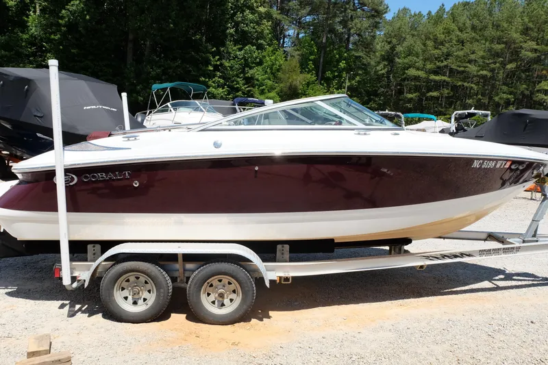 The Image of 2004 Cobalt 200 boat on trailer, parked outdoors with trees in the background. - 0