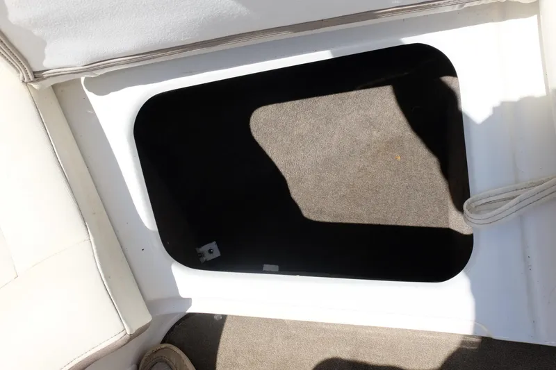 Slide: The Image of Open storage compartment in 2004 Cobalt 200 boat, featuring carpeted interior and white trim. - 12