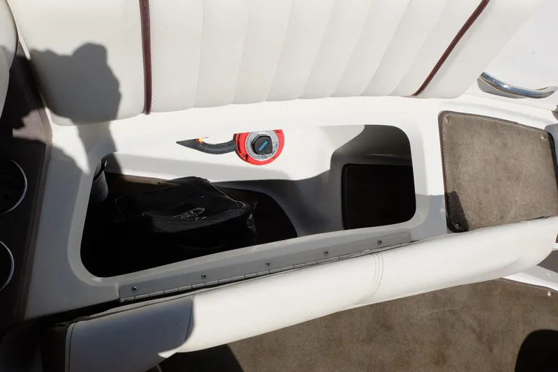 Slide: The Image of Open storage compartment in 2004 Cobalt 200 boat with white seating and visible wiring. - 24