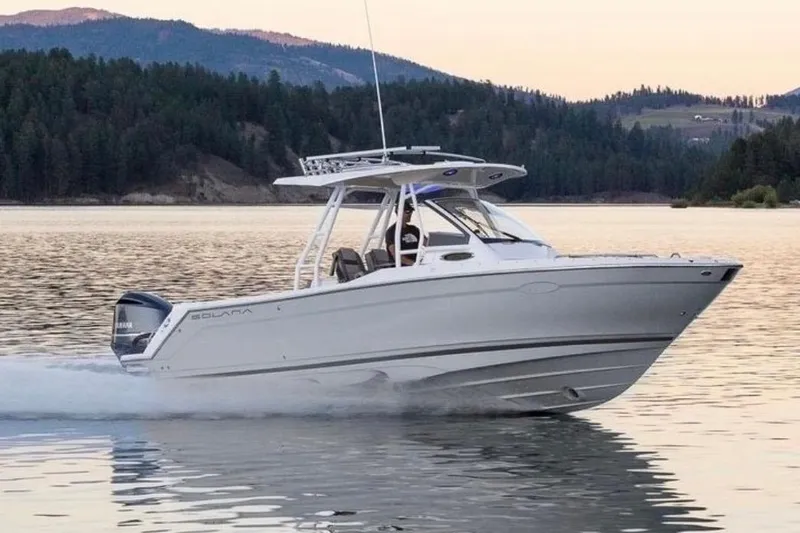 Slide: The Image of 2020 Solara S-250 CW boat cruising on a serene lake with forested hills in the background. - 1