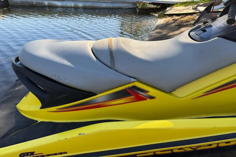 Slide: The Image of 2004 Sea-Doo GTX 4-TEC Supercharged jet ski with yellow and gray seat, docked by water. - 11