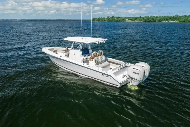 The Image of 2026 Jupiter 32 boat on open water with Yamaha engines, clear sky, and distant shoreline. - 0