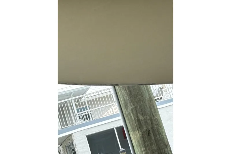 Slide: The Image of A wooden post near a building with white railings and windows. - 43