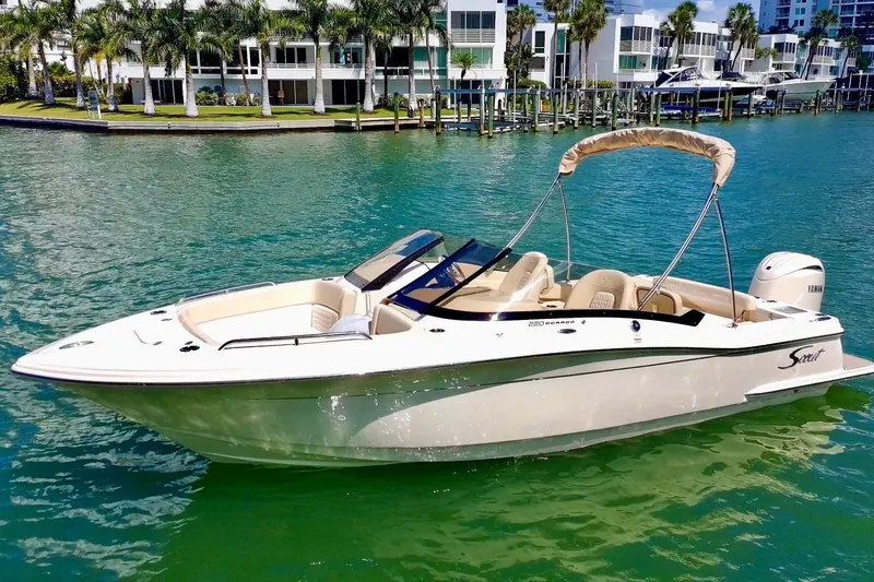 The Image of 2026 Scout 220 Dorado boat on clear water with modern buildings in the background. - 0