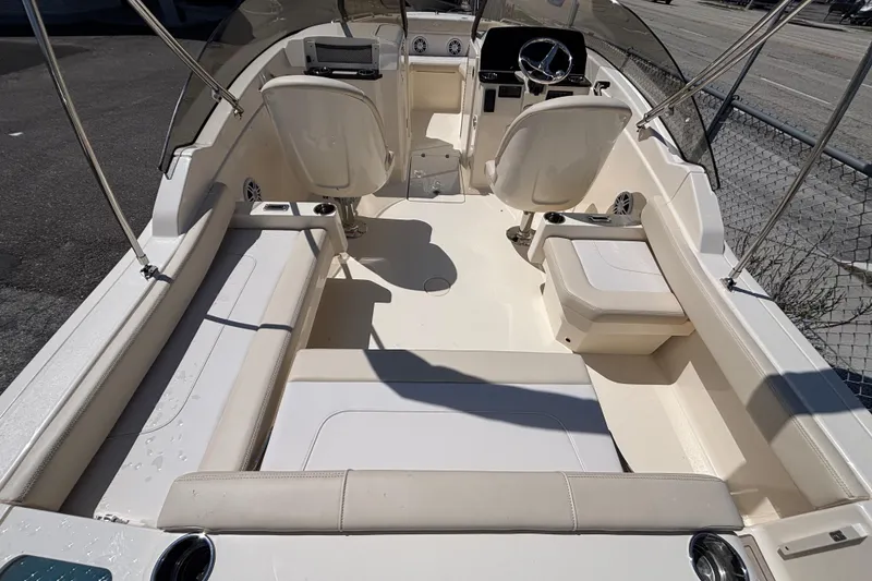 Slide: The Image of 2026 Scout 220 Dorado boat interior with seating and steering wheel, docked outdoors. - 10