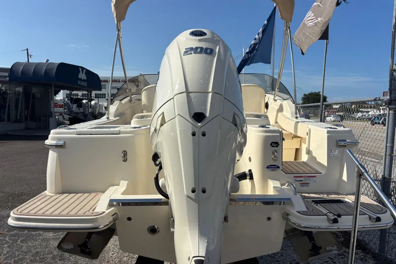 Slide: The Image of 2026 Scout 220 Dorado boat with powerful outboard motor, displayed at a dealership. - 6