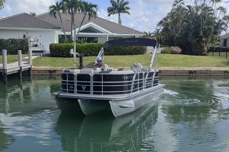 Slide: The Image of 2021 Trifecta 22RF LE pontoon boat cruising near waterfront homes. - 3