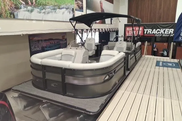 Slide: The Image of 2022 Crest Classic Platinum 220 pontoon boat displayed indoors on a wooden dock. - 1