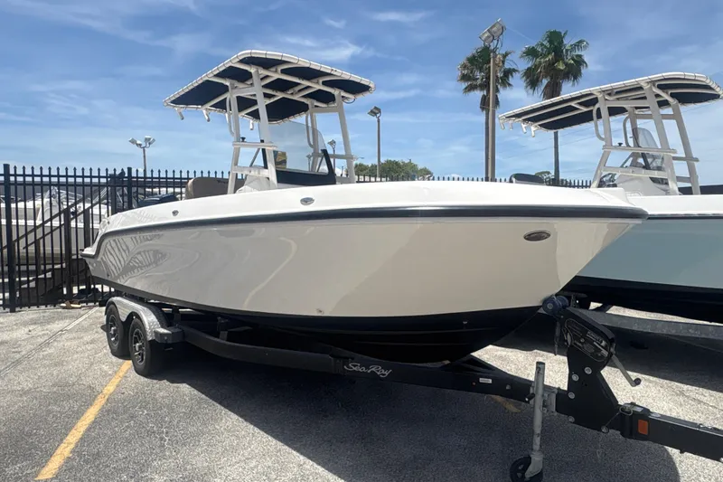 The Image of 2023 Bayliner Trophy T22CC boat on trailer, parked outdoors under clear sky. - 1
