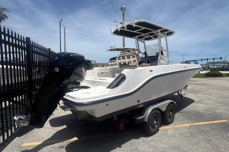 Slide: The Image of 2023 Bayliner Trophy T22CC boat on trailer, parked outdoors under clear sky. - 4