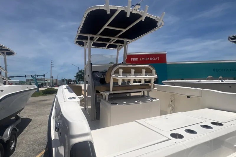 Slide: The Image of 2023 Bayliner Trophy T22CC boat with T-top, docked outdoors under clear sky. - 6