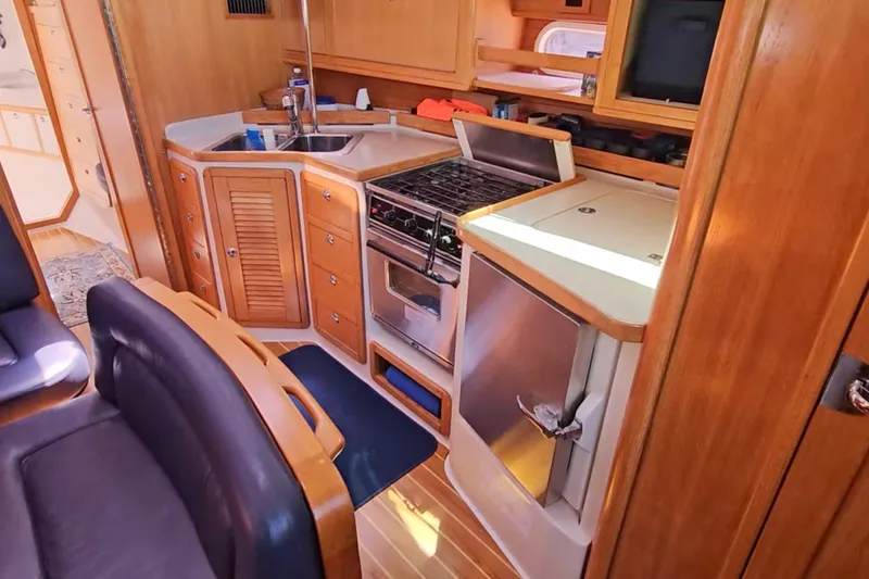 Slide: The Image of Interior of a 2006 Catalina 42 MkII yacht, featuring a compact kitchen with wooden cabinetry. - 20