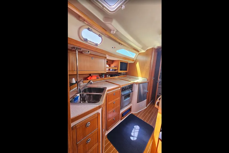 Slide: The Image of Interior of 2006 Catalina 42 MkII yacht, featuring a compact kitchen with wooden cabinetry. - 22