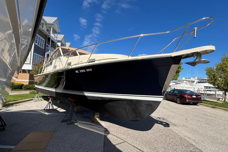 The Image of 2006 Mainship Pilot 34 Sedan boat on stands, dockside, under clear blue sky. - 0