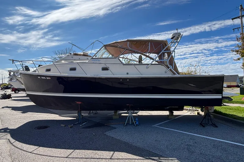 Slide: The Image of 2006 Mainship Pilot 34 Sedan boat on stands, parked outdoors under a clear sky. - 2