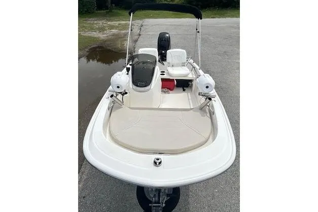 Slide: The Image of 2020 Boston Whaler 130 Super Sport boat with seating and console, parked on pavement. - 13