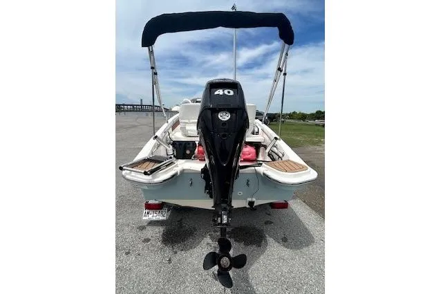 Slide: The Image of 2020 Boston Whaler 130 Super Sport boat with outboard motor and canopy, parked on pavement. - 3
