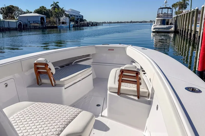Slide: The Image of Manufacturer Provided Image: 2026 Jupiter 34 boat interior with cushioned seating, docked by calm waters. - 3