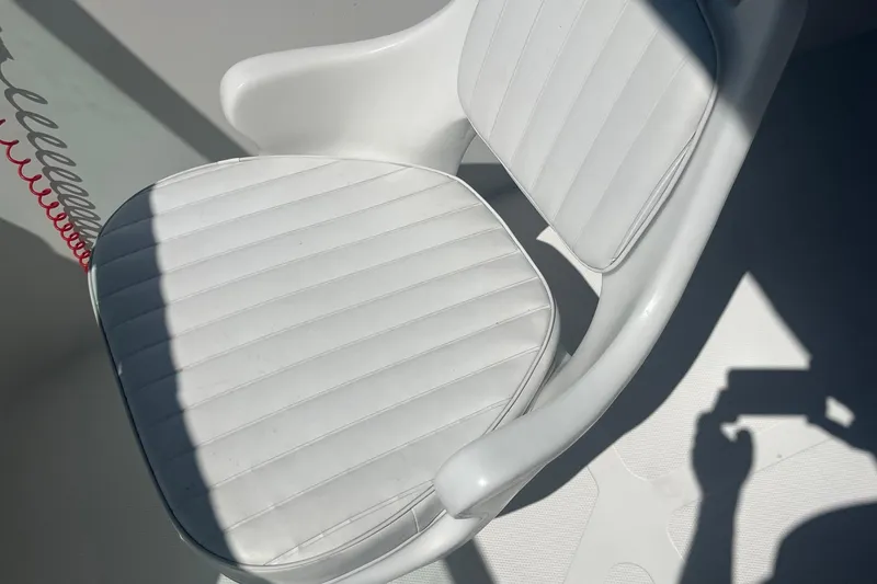 Slide: The Image of White cushioned seat on 2007 NauticStar 2000XSDC Offshore boat, with shadow and red coiled cord. - 7