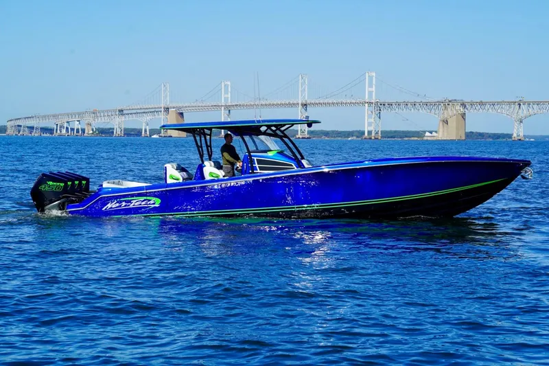 The Image of 2023 Nor-Tech 390 Sport Center Console boat cruising near a large bridge on a sunny day. - 0