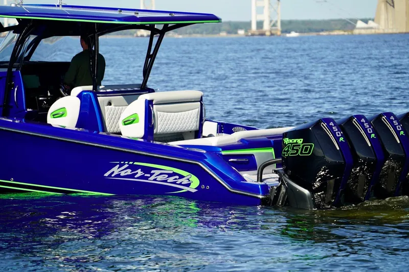 Slide: The Image of 2023 Nor-Tech 390 Sport Center Console boat with powerful outboard engines on water. - 14