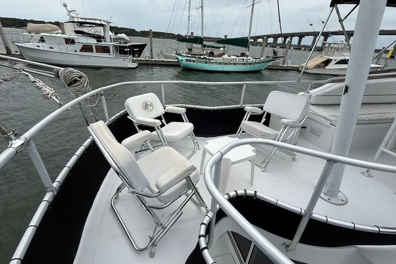 Slide: The Image of Deck of 1998 Mainship 350 Trawler with chairs, docked near other boats. - 13