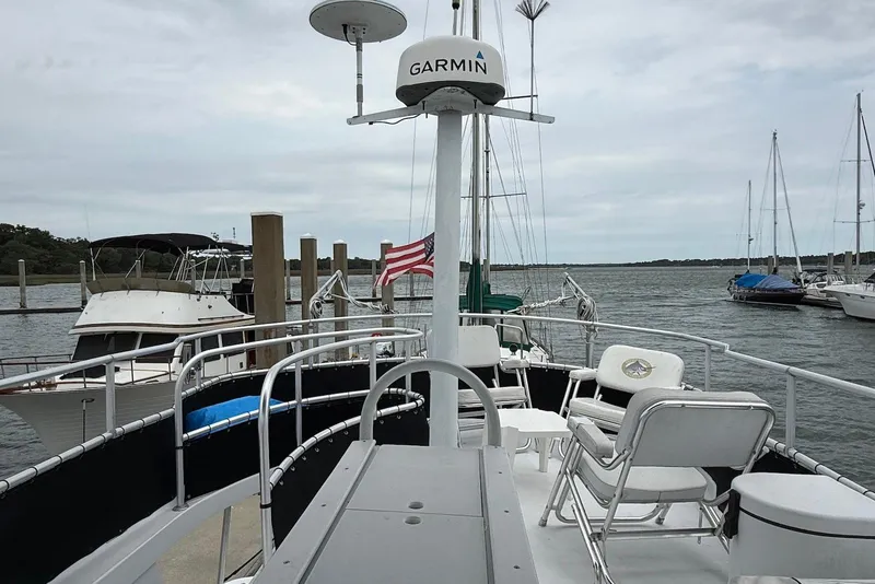 Slide: The Image of 1998 Mainship 350 Trawler docked, featuring deck chairs and Garmin radar, with marina view. - 15